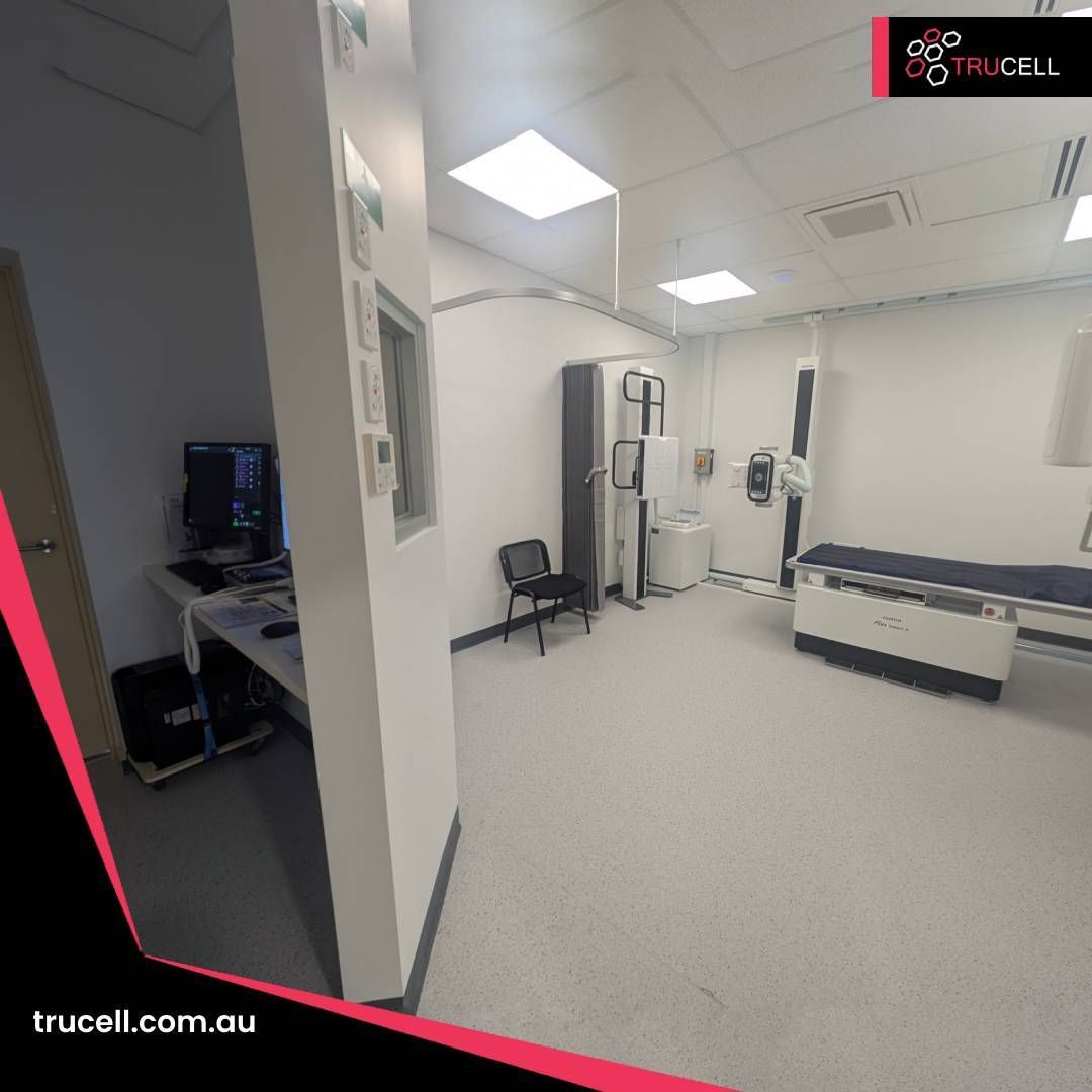 Sala de rayos X de Care Plus Imaging Doncaster: equipo Fujifilm con detector de panel plano, estación clínica con monitor de paciente multicanal y el área de control del técnico visible a través de la ventana plomada