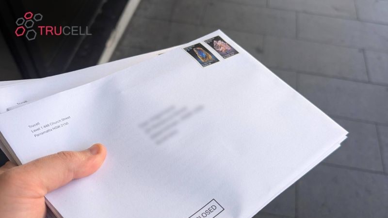 Un puñado de sobres del kit DICOM de Trucell en mano, listos para ser enviados a radiólogos en Australia, con dirección de remitente Level 1, 448 Church Street, Parramatta