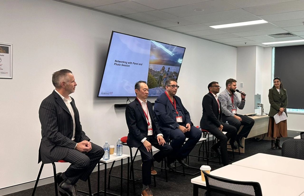 Cinco panelistas de la industria sentados en taburetes en el Industry Fireside Chat del campus Sydney de la Universidad de Tasmania, una discusión sobre empleabilidad, liderazgo y desarrollo profesional con una moderadora estudiantil a la derecha presentando el segmento de networking y sesión de fotos